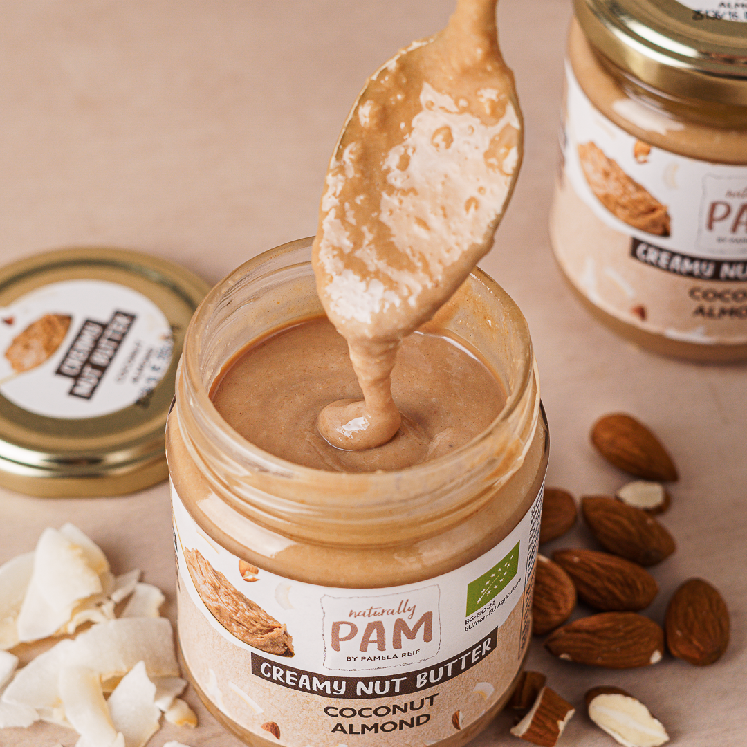 Naturally Pam Nussbutter mit Kokosnuss und Mandeln, cremig und gesünder, in einem Glas mit Kokosnuss und Mandeln.