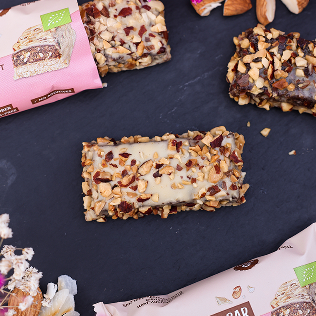 Naturally Pam Cake Bar mit Mandeln und Kokosnuss, nährstoffreicher Snack in Riegel-Form, auf weißem Hintergrund.