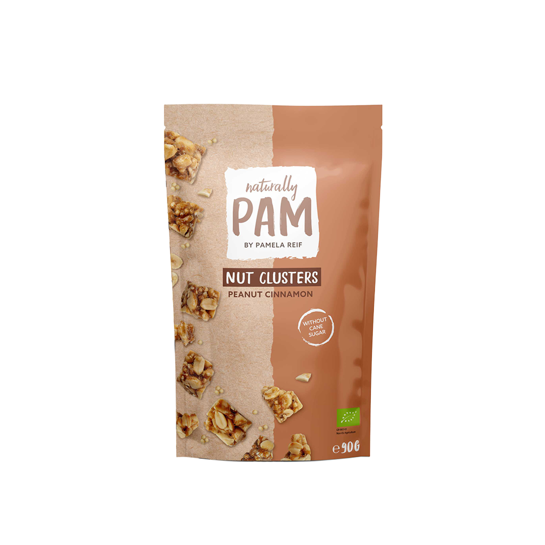 Natürlich Pam Peanut Cinnamon Nuss-Klumpen, knusprige Gebäckstücke aus Erdnüssen und Zimt, auf einem weißen Teller.